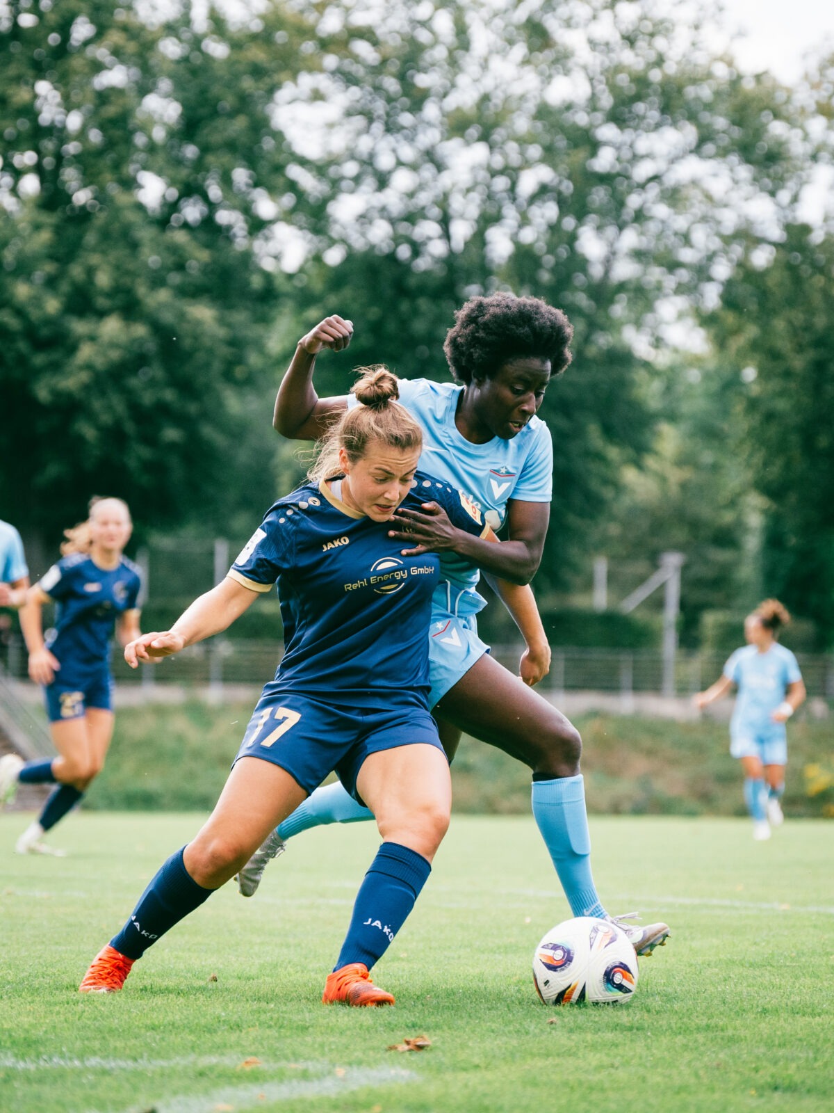 Eunice Beckmann, im hellblauen Trikot des FC Viktoria Berlin, hält den Arm ihrer Gegenspielerin im dunkelblauen Trikot der SG Andernach, Leonie Wäschenbach. Wäschenbach ist vor Beckmann.