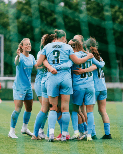 Das Team des FC Viktoria Berlin feiert in einer Jubeltraube einen Treffer gegen Bochum. Alle tragen das hellblaue Heimtrikot, zu erkennen sind vorne Anna Ursem mit der Rückennummer 3 und Aylin Yaren mit der 25. Foto: Kai Heuser (@heuserkampf).